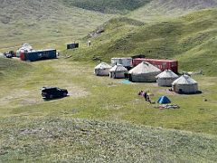 06A Yurts, trailers, tents and cars in the green fields near the large lake on day hike to Tulpar Lake from Ak-Sai Travel Lenin Peak Base Camp 3600m